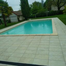 Piscine avec carrelage clair, élégant et bien intégré au jardin.